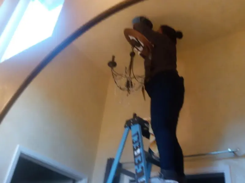 Electrician installing a chandelier in a Dumas residence